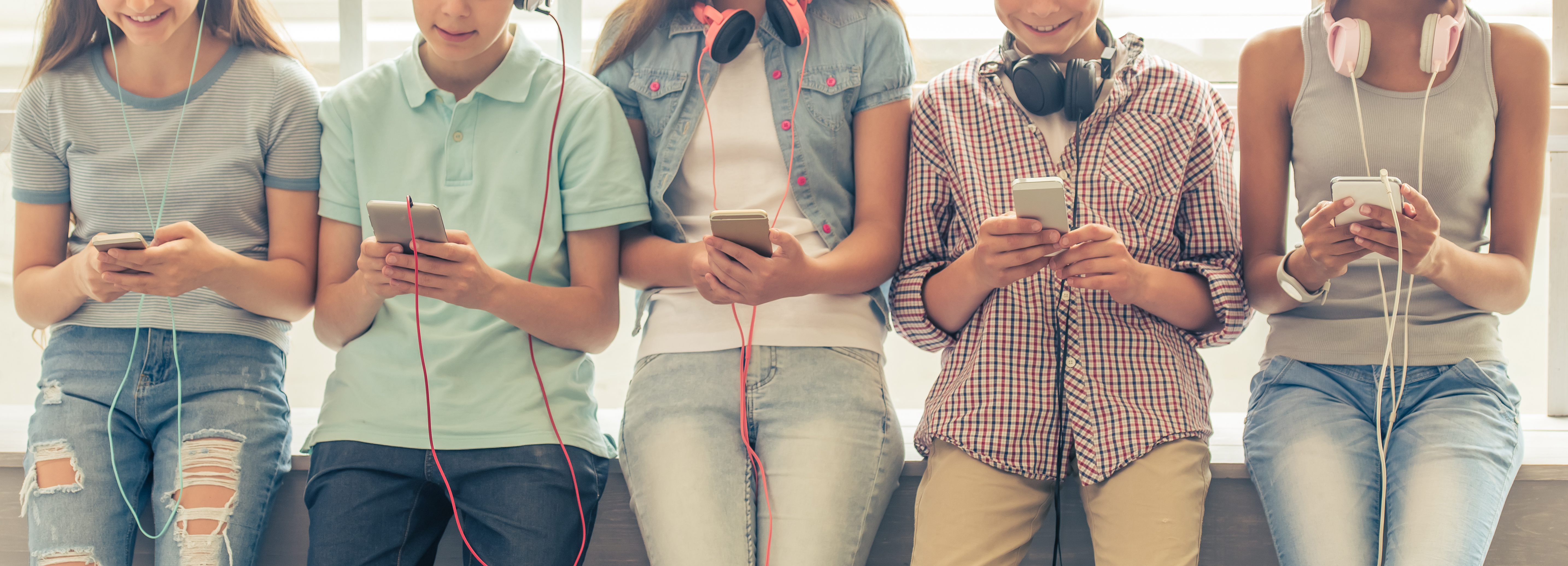 Kids and Teens lined up with headphones and smartphones listening to audiobooks